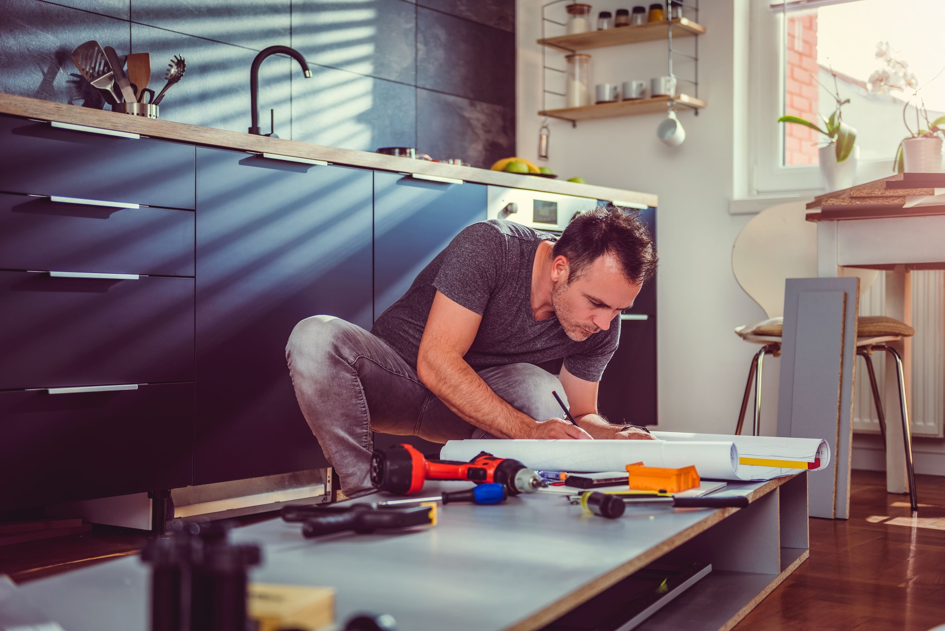 Man checking blueprints while building kitchen cabinets